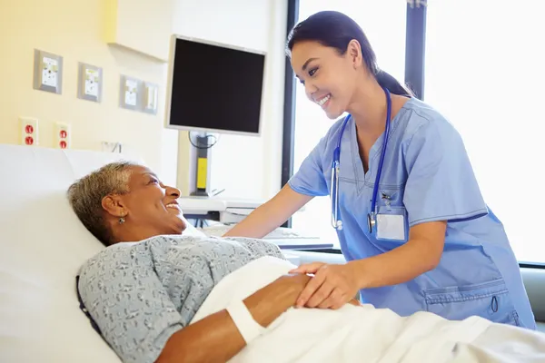A nurse is smiling at an older patient.